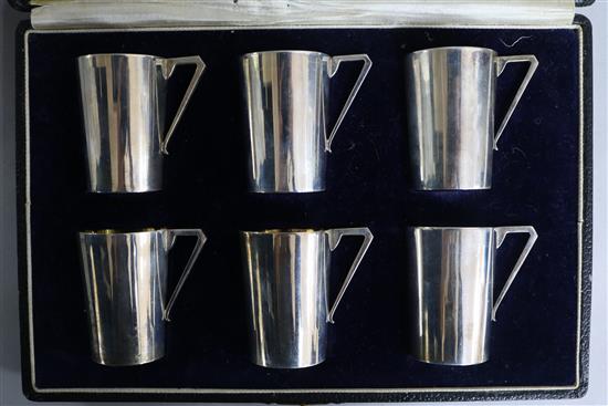 A cased set of six Indian white metal cups with angular handles, by J. Boseck & Co, Calcutta, 52mm.